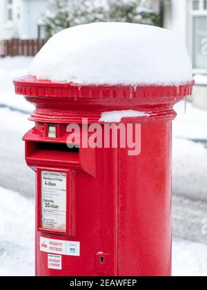 Snow covered red priority postbox Stoneyburn village, West Lothian. Stock Photo