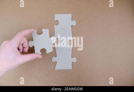 Man's hand attaches the missing piece of the puzzle. Stock Photo