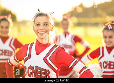 Portrait of an happy young cheerleader in action outdoors - Group of girlfriends during cheerleading sport training at high school Stock Photo