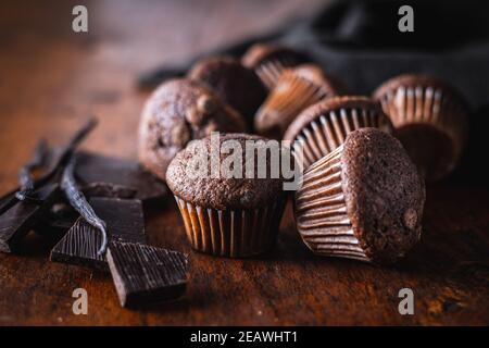 Chocolate muffins. Sweet dark cupcakes with chocolate and vanilla pods on wooden table. Stock Photo