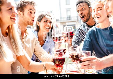 Happy multiracial friends having fun drinking and toasting red wine at lunch party - Young people eating bbq food at restaurant winery together Stock Photo