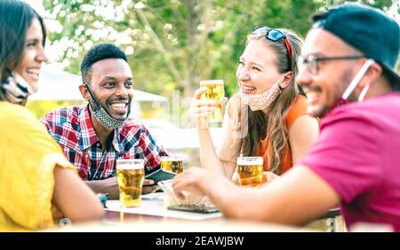 Friends drinking beer with opened face masks - New normal lifestyle concept with people having fun together talking on happy hour at brewery bar