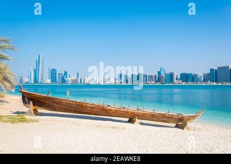 Wooden boat at the Heritage Village, in front of the Abu Dhabi skyline, United Arab Emirates Stock Photo