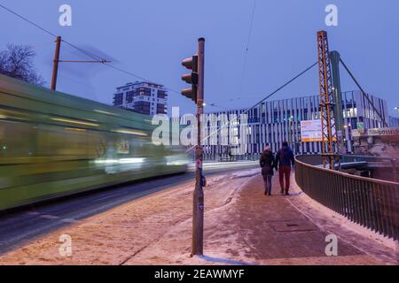 Outdoor night view on the sidewalk beside which covered by snow and ice beside moving light rail tram in Düsseldorf, Germany. Stock Photo