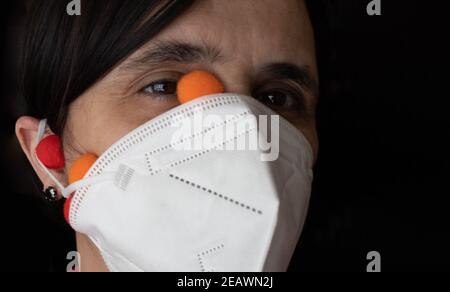 woman with white ffp2 mask protecting from Covid19 with the rubber band in the ear crossed and with colored viruses coming out due to its bad position Stock Photo
