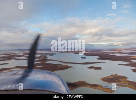 View from Cessna 207 airplane window, flying in the Canadian Arctic above waterbodies heading towards Tuktoyaktuk, Northwest Territories. Stock Photo