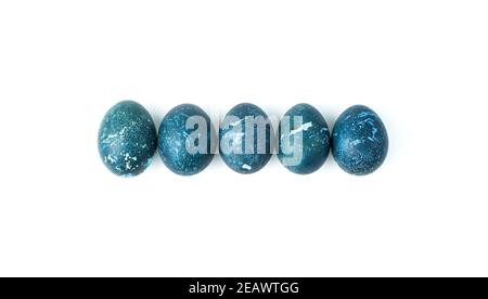 Five dark blue eggs are laid out in a row on a white background. Stock Photo