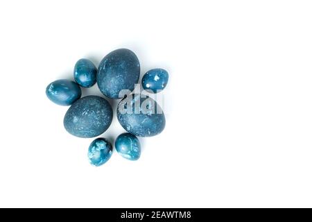 Easter eggs painted with natural dark blue dye on a white background. Stock Photo