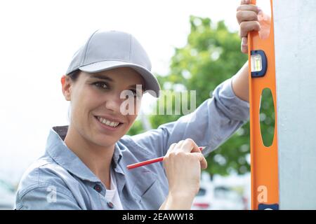 female construction worker checking vertical level of the wall Stock Photo