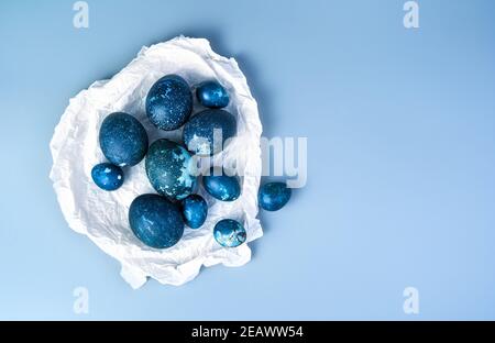 A set of quail and chicken eggs in parchment paper on a blue background. Stock Photo