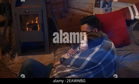Couple sitting by the burning fireplace in a cozy house . High quality photo Stock Photo