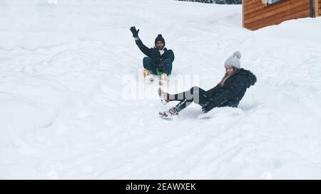 Winter outdoors entertainment. Young man and woman sliding on the snow. High quality photo Stock Photo