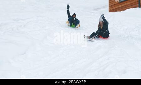 Young couple on Christmas holidays riding sledge in the snow. High quality photo Stock Photo