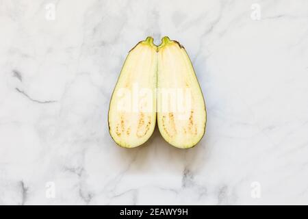 Isolated aubergine sliced at the middle isolated over a white marble background viewed from above - flatlay look Stock Photo