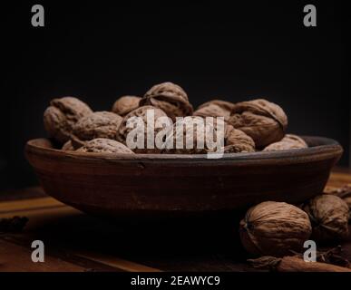 Nuts. Walnut kernels and whole walnuts on a dark wooden table. Black background  Stock Photo