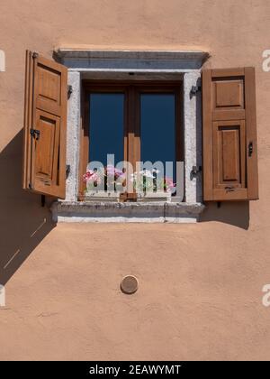 close up of a shuttered house window with flowers in a planter box at trento, italy Stock Photo