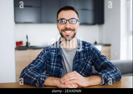 Webcam portrait of happy freelancer guy during video conference, he looks at the camera and smiling. Young adult stylish intelligent man wearing eyegl Stock Photo