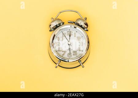 Antique vintage analog alarm clock on yellow background concept time Stock Photo