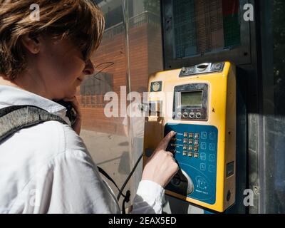 Baku Azerbaijan - May 2, 2019: Young woman using coin phone on the corner of a street in central Baku Stock Photo