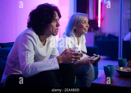 Photo of young couple playing video games at home at night Stock Photo