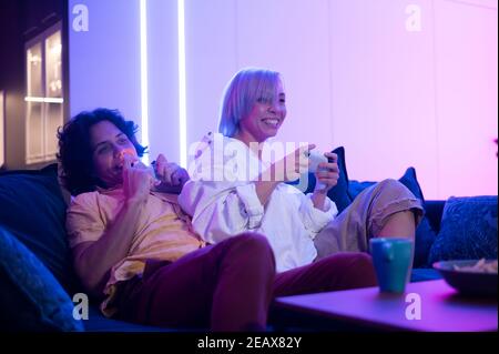 Portrait of emotional young couple playing video game at home. Stock Photo