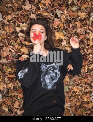 girl lying in and playing with leaves Stock Photo