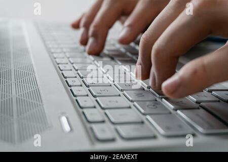 a man's hands typing on the keyboard of a computer all gray and modern Stock Photo