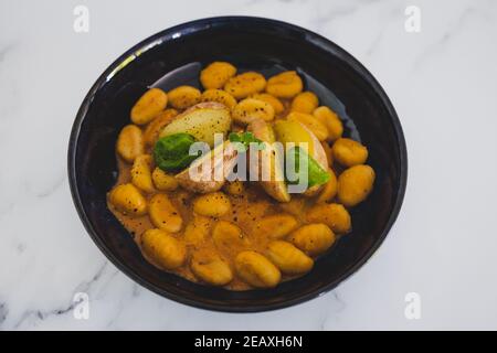 healthy plant-based food recipes, vegan gnocchi with dairy-free pumpkin sauce and roasted potatoes with basil Stock Photo