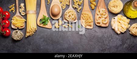 Various pasta in spoons, tomatoes and olive oil. Top view flat lay Stock Photo