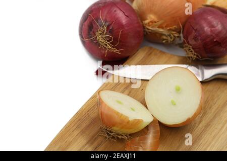 White and red onions cut on a wooden board with silver knife isolated on white background with copy space Stock Photo