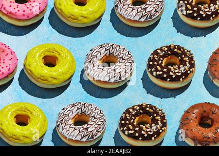 Donuts pattern with white, yellow and brown glaze on a blue background. Stock Photo