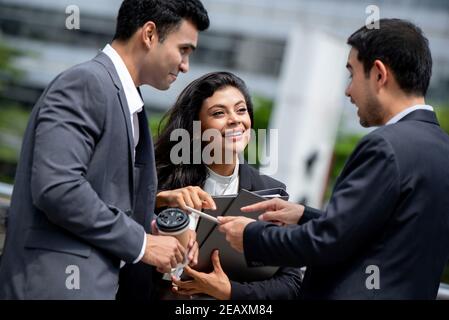 Happy active Asian businesspeople talking and meeting together outside office Stock Photo