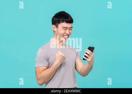 Cool young Asian man having fun chatting with his friend via vedio call isolated on light blue studio background Stock Photo