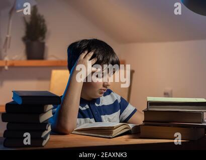 The idea of a child's participation in learning. the focused face of a boy reading a book in his room. the emotion of slight tension and concentration Stock Photo