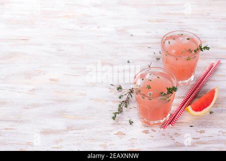 Healthy summer drink grapefruit lemonade with thyme in glasses with ice on a wooden surface, free space, horizontal Stock Photo