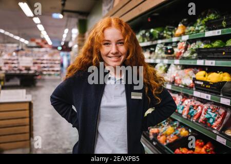 Portrait of young hypermarket employee. Female student on a holiday job in a grocery store. Stock Photo