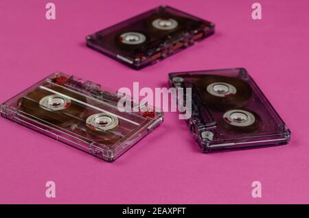 Collecting music recordings concept. Close-up of three audio cassettes with music recordings on a pink background. Selective focus. Stock Photo