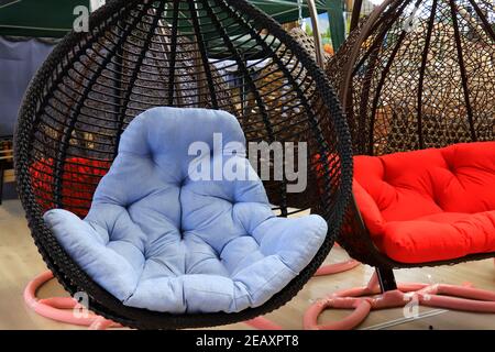 Garden wicker furniture. Hanging swing with blue soft pillow. Beautiful, modern home furniture, rattan sofa, seat Stock Photo