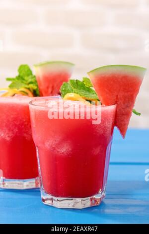 Colorful tropical fresh watermelon smoothie summer drinks in the glasses on blue wood table background Stock Photo
