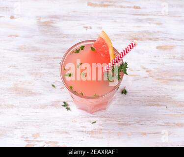 Healthy summer drink grapefruit lemonade with thyme in glasses with ice on a wooden surface, horizontal Stock Photo