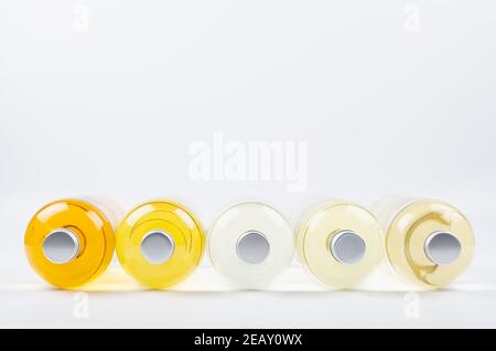 Collection lying transparent bottles with different pale colors liquid, cosmetic product, perfume or drink and blank silver cap on white background as Stock Photo