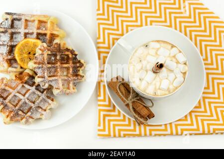 Early breakfast coffee with marshmallows and a stick of cinnamon and Belgian waffles Stock Photo