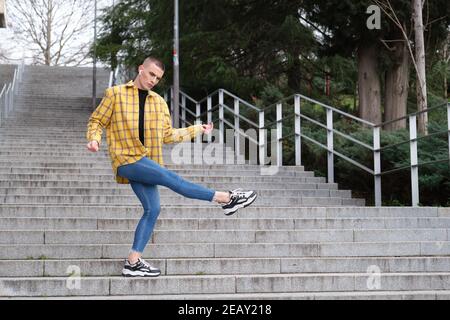 Handsome young man wearing make up, dancing on stairs. Non binary androgynous guy. Stock Photo