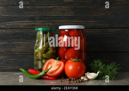 Jars with pickled tomatoes and cucumbers on wooden background Stock Photo