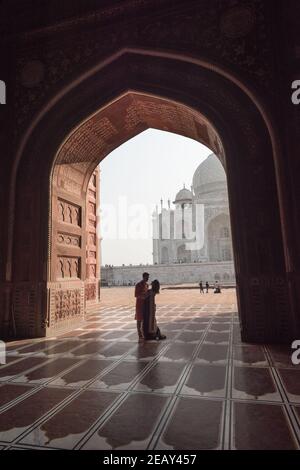 Romantic Couple near Taj Mahal. View in black arch silhouette from the mosque in Agra, Uttar Pradesh, India Stock Photo