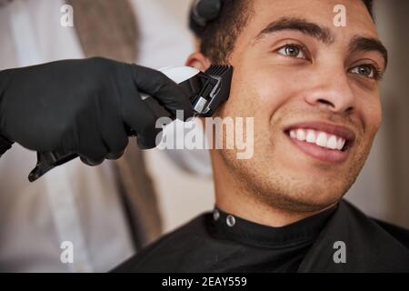 Barber hand holding hair instrument near the customer in beauty salon Stock Photo