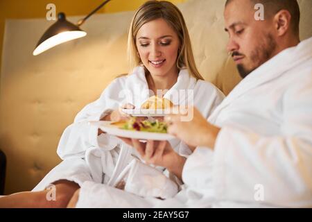 Newlyweds in terry bathrobes having breakfast together Stock Photo