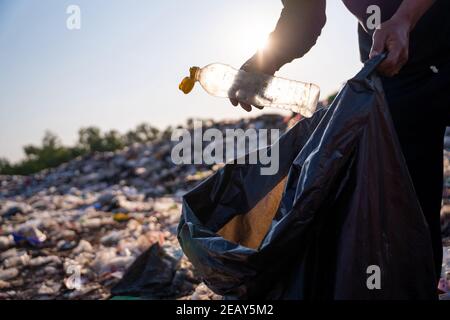 Close up hand collecting plastic bottle garbage for recycling concept reuse at the waste disposal site. Stock Photo