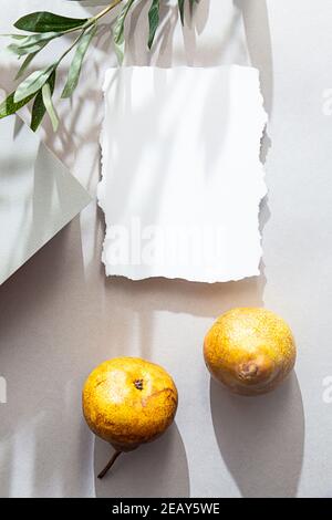 Blank sheet paper, pears, long shadow on a light background. Summer minimalistic stationary still life. Invantation, flat lay Stock Photo