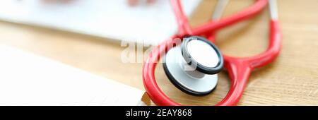 Red stethoscope is lying on table Stock Photo